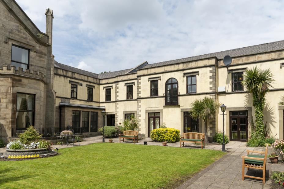 external shot of the home showing the home and a grassy area with benches